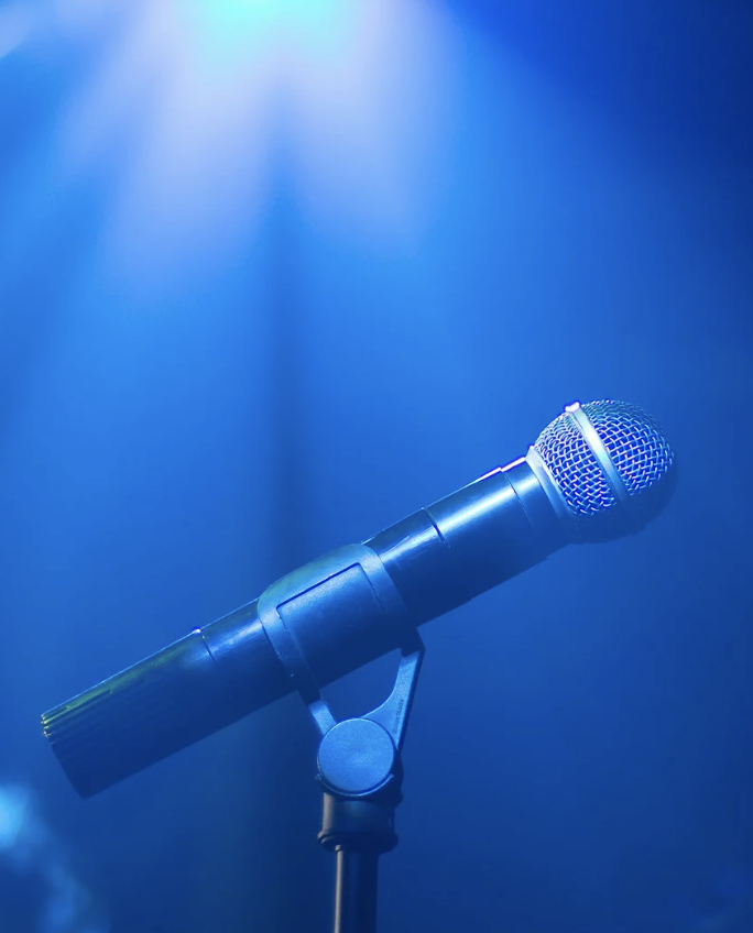 A microphone stands alone under a spotlight.
