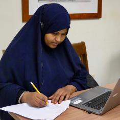 Learner works at computer with headphones