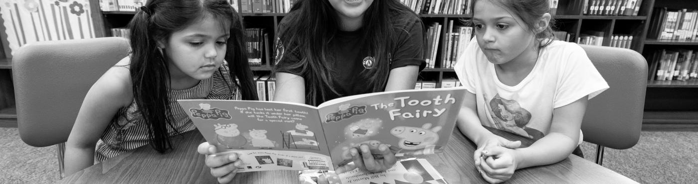 Summer Reads AmeriCorps member reads with two children