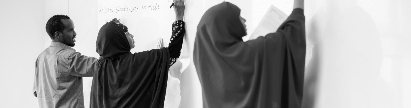 Adult students write on a whiteboard