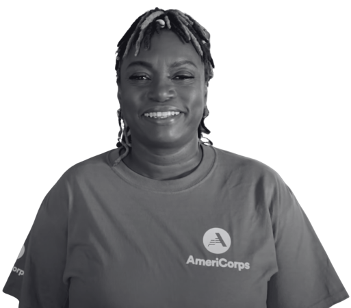 Woman smiling at the camera. She is wearing a t-shirt with the AmeriCorps logo.