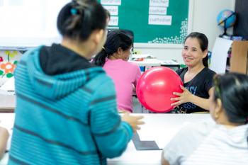 Learners in a circle tossing a large ball