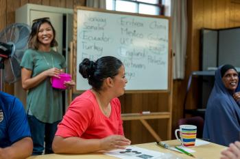 Teacher standing by a whiteboard with leaners playing bingo