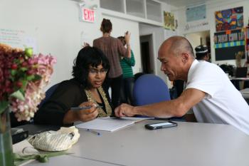 A tutor helps an adult learner write in their notebook