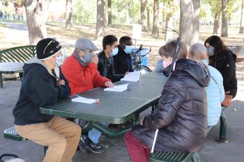 Open Door Book Club members sit outside at a picnic table with books and masks