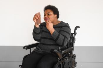 a black woman in a wheelchair is putting on lip gloss