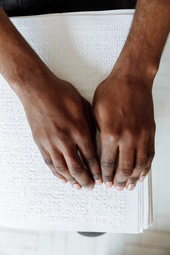 Zoomed in photo of hands reading a large white braille folio