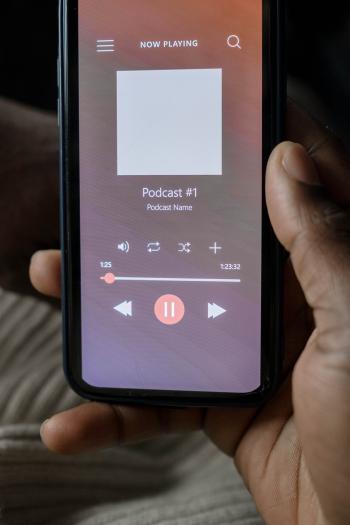the image shows a hand holding a cell phone that is playing a podcast