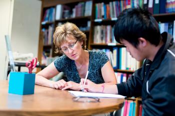 A volunteer works with a learning sitting at a table