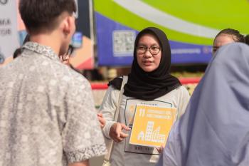 a woman wearing a hijab and a sign talks to a man