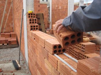 hands in work gloves holding a trowel and building a brick wall