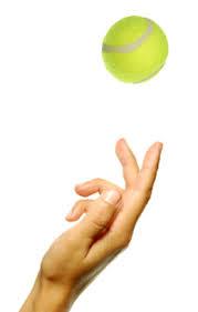 a hand tossing a yellow tennis ball
