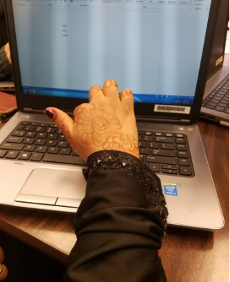 woman's hand with henna typing on a laptop