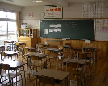 classroom with desks and chairs facing a chalkboard