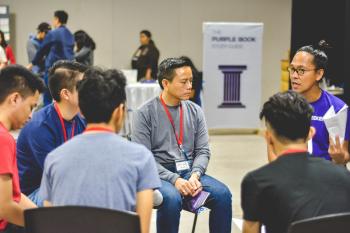 group of Asian men sitting in a circle and talking