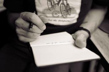 hands holding a notebook and a pen