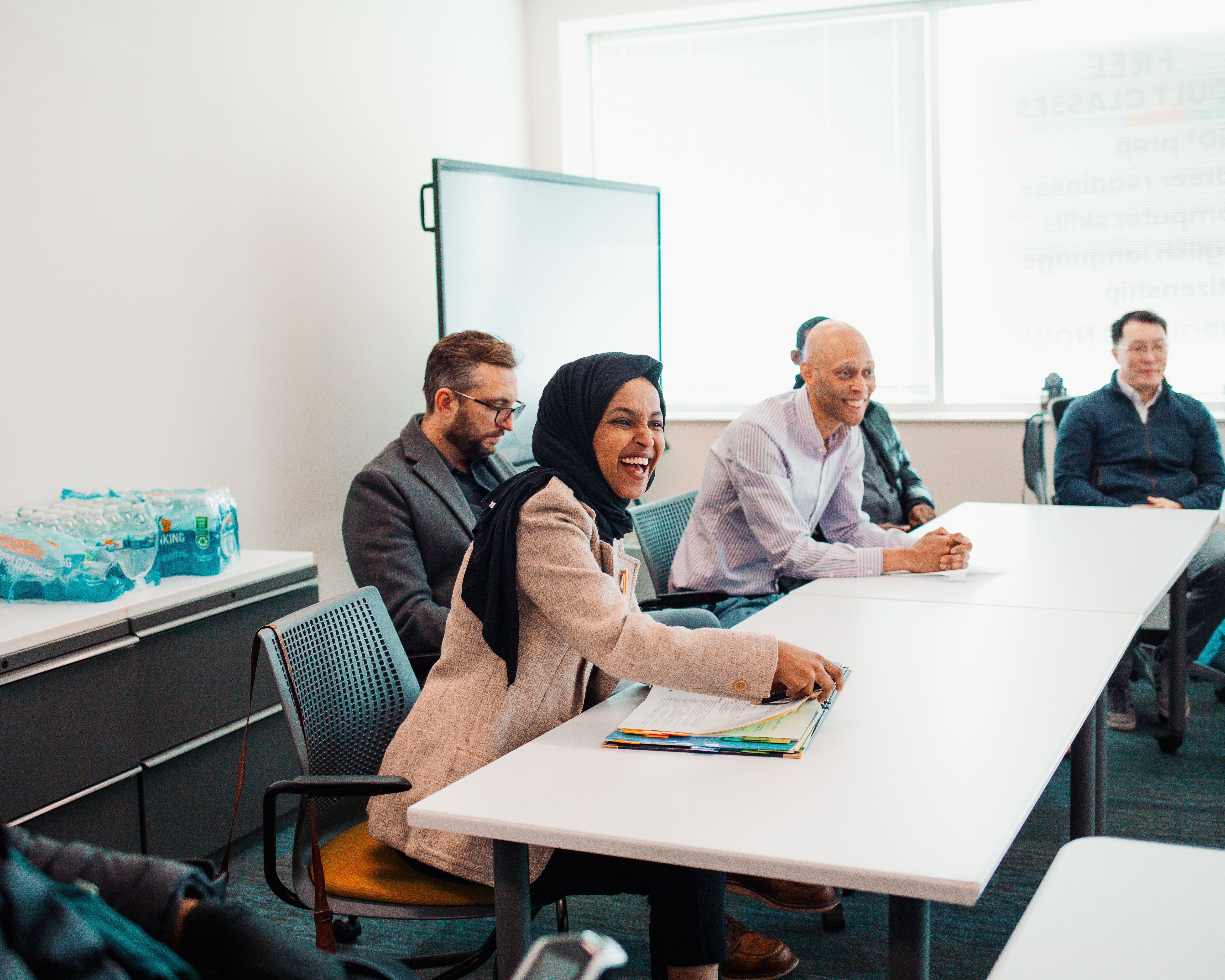 Ilhan Omar laughs alongside Literacy Minnesota President Anton Jones