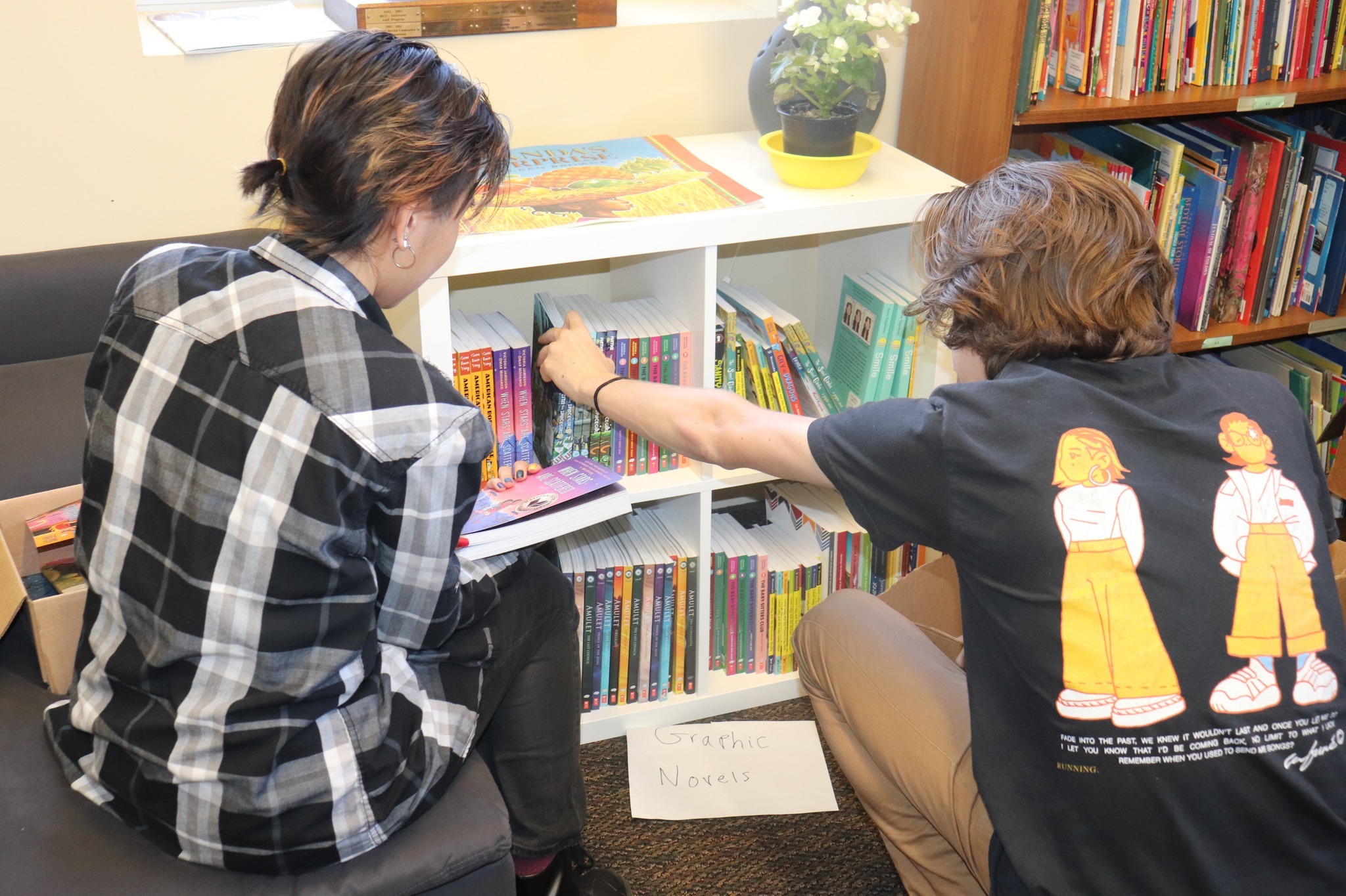 Two summer reads mentors choose books on a bookshelf.