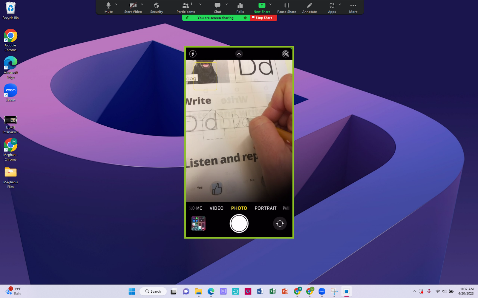 The image shows the shared screen of an iPhone on a desktop. The sharer is showing a hand writing in a phonics workbook.