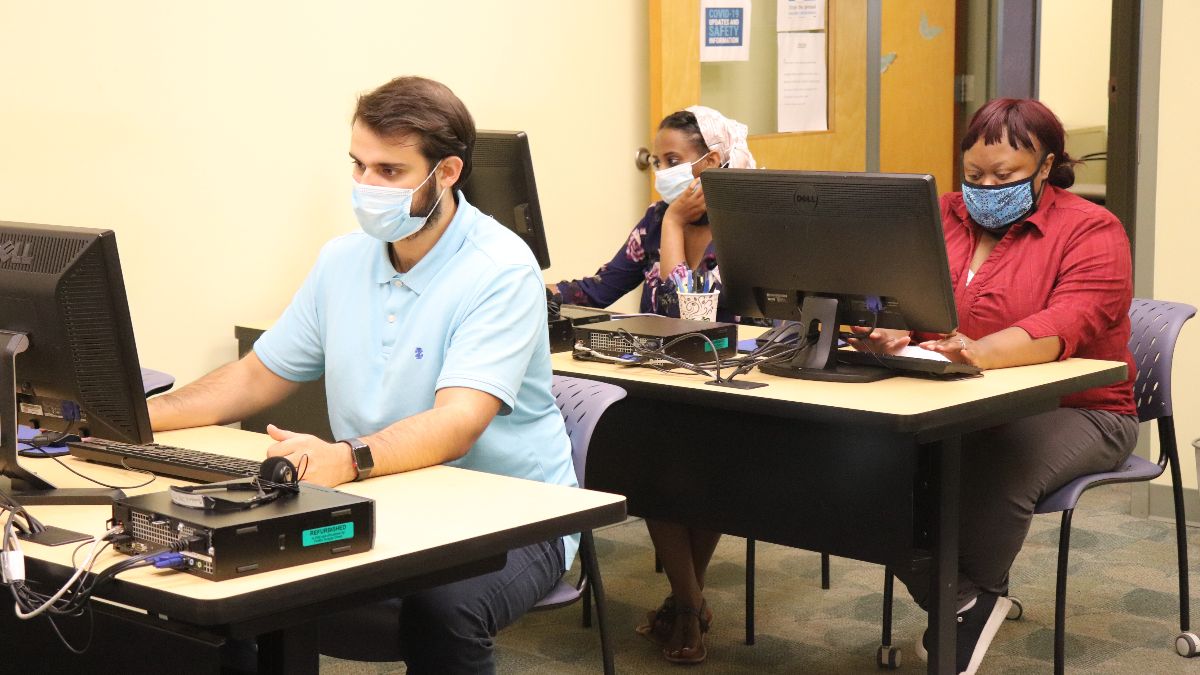 Student sit at computer work stations in class.